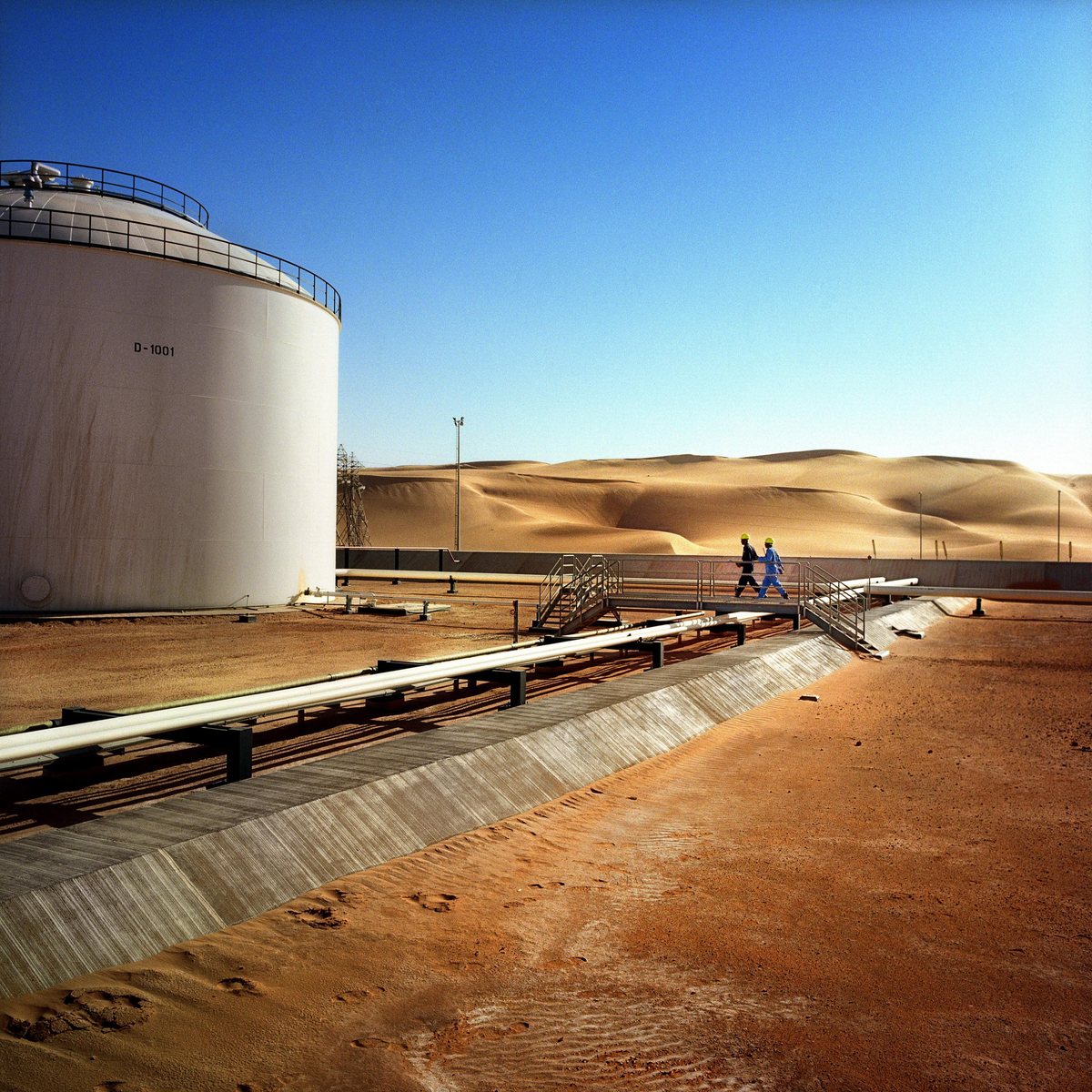 Technicians at an oil storage tank facility at dusk